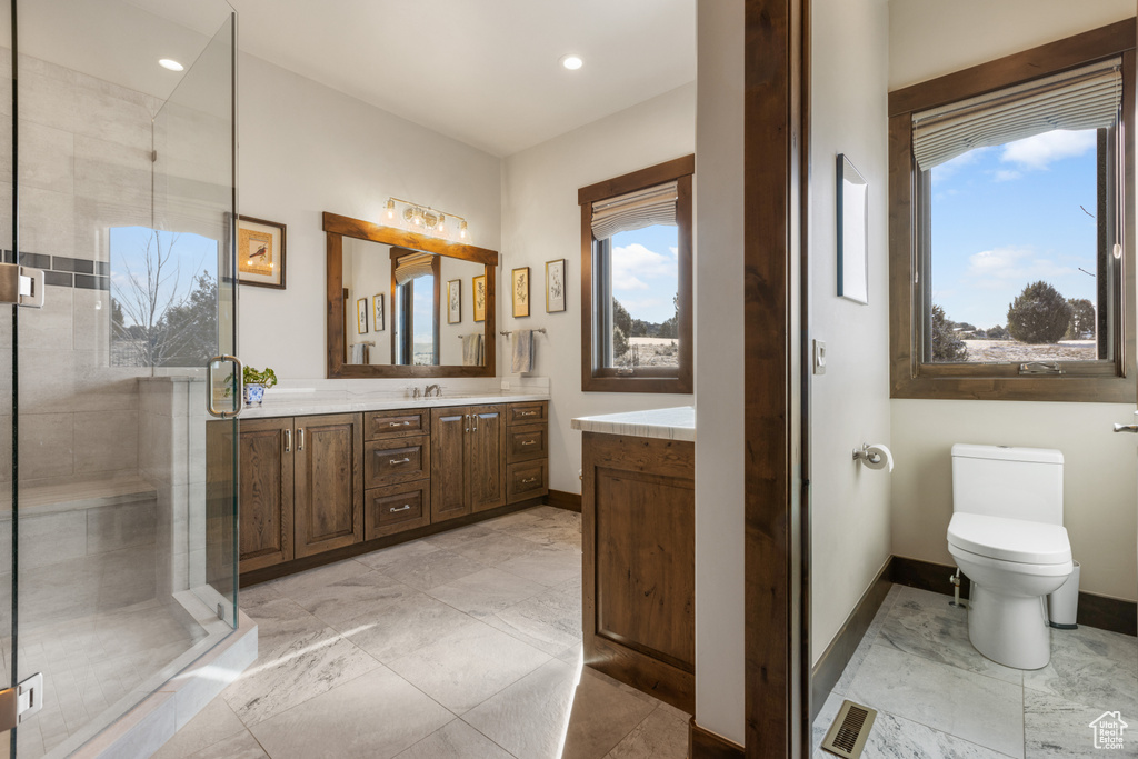 Bathroom with plenty of natural light, large vanity, toilet, and tile flooring