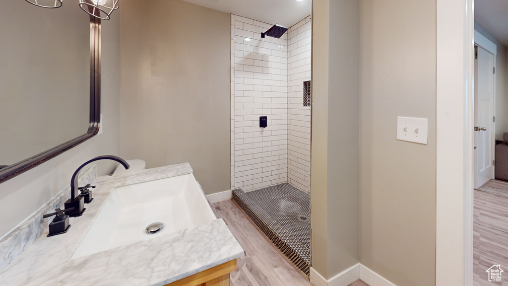 Bathroom featuring vanity, tiled shower, and hardwood / wood-style flooring