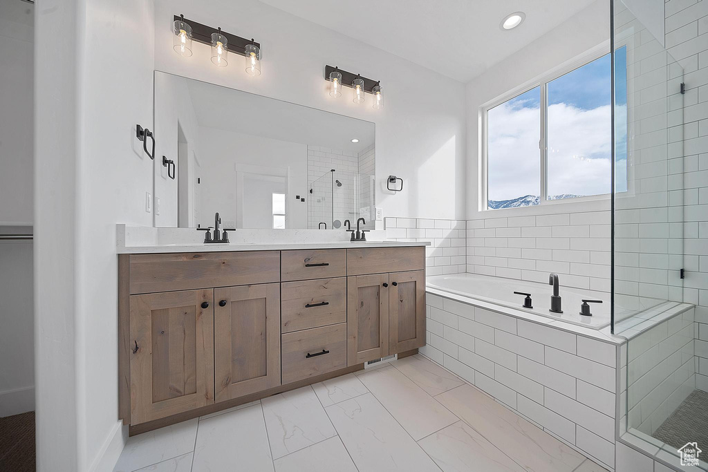 Bathroom featuring dual vanity, plus walk in shower, and tile floors