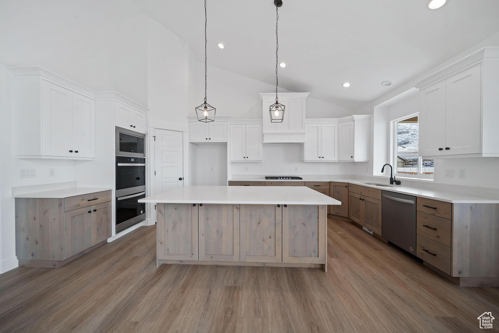 Kitchen featuring hardwood / wood-style floors, stainless steel appliances, a center island, and white cabinetry