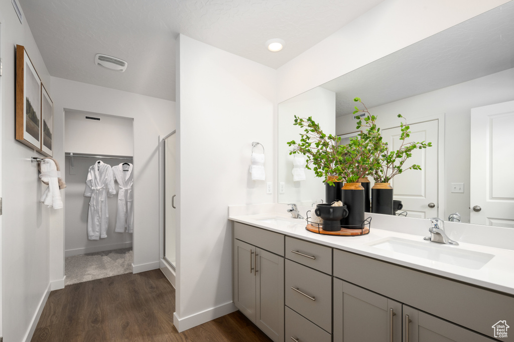 Bathroom featuring walk in shower, wood-type flooring, and dual bowl vanity