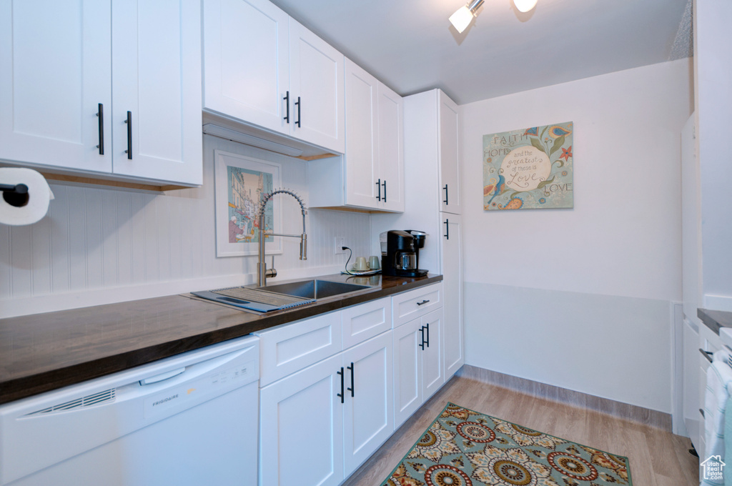 Kitchen featuring white cabinets, dishwasher, sink, and light hardwood / wood-style flooring