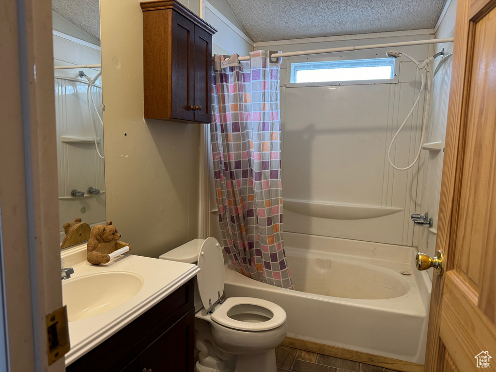 Full bathroom featuring shower / bath combo with shower curtain, toilet, and a textured ceiling