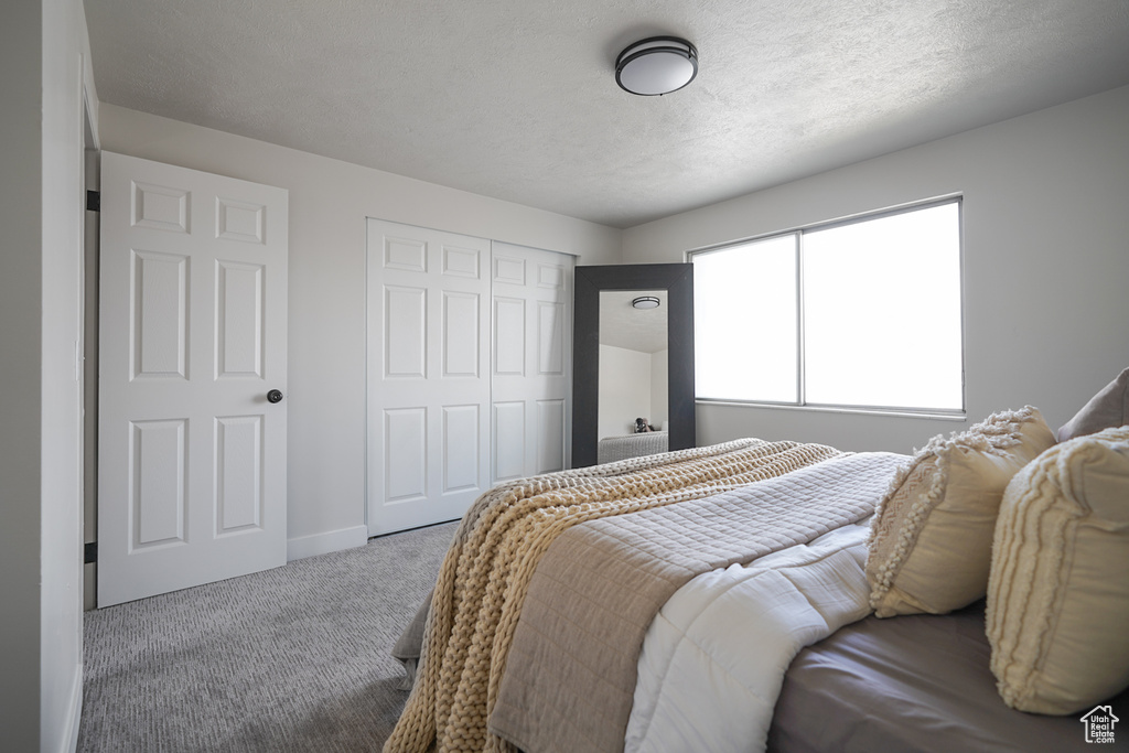 Bedroom with a closet, light carpet, and a textured ceiling