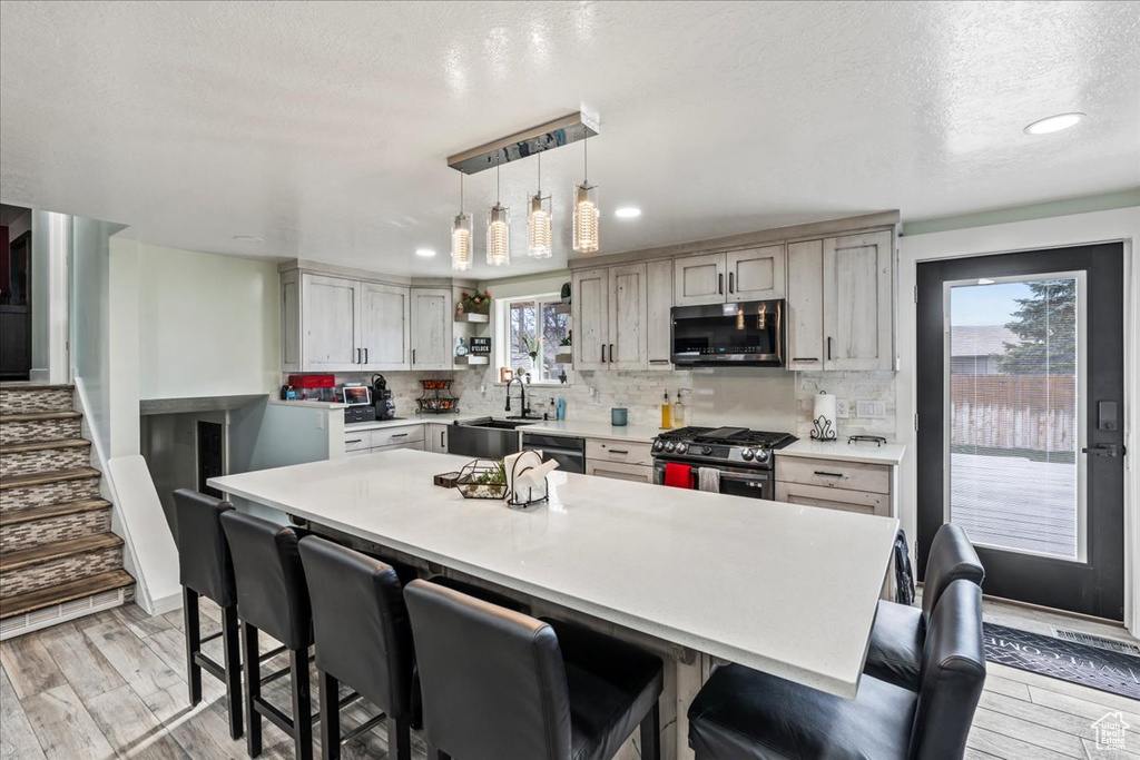Kitchen with a breakfast bar area, appliances with stainless steel finishes, and a wealth of natural light