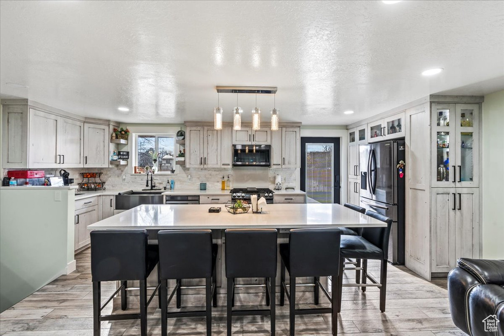 Kitchen featuring light wood-type flooring, stainless steel appliances, a center island, and a breakfast bar area