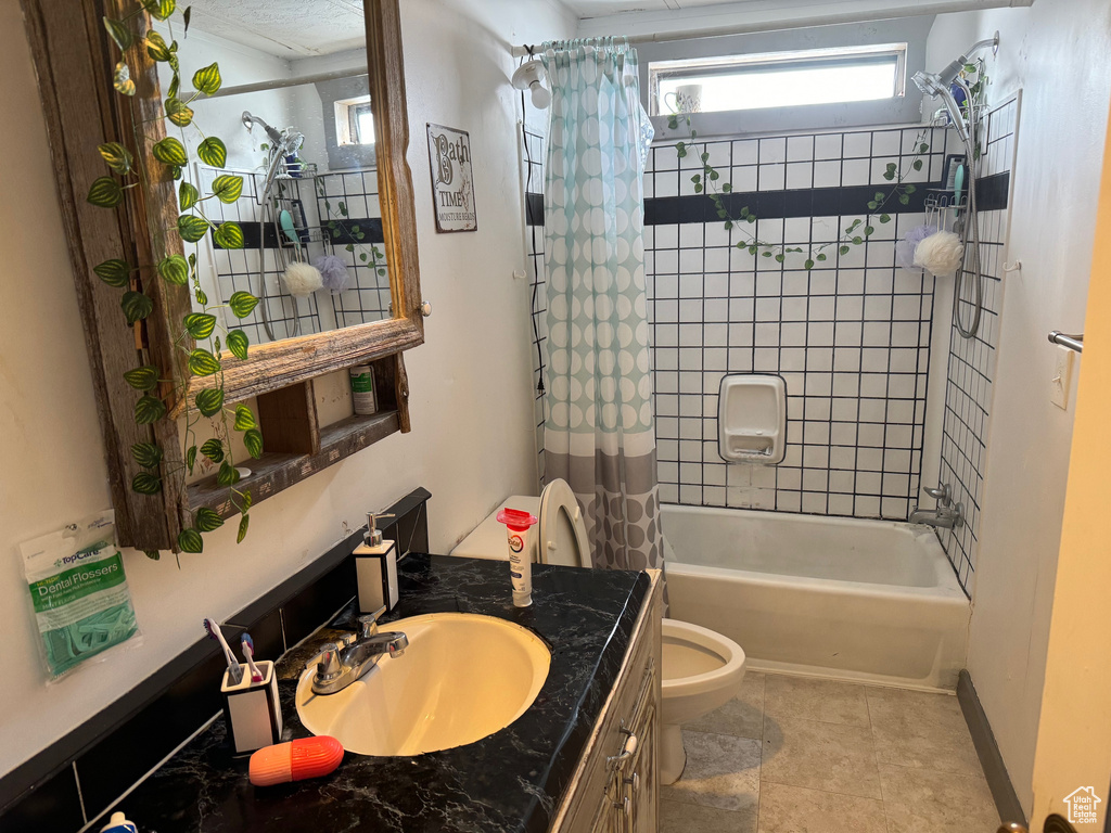 Full bathroom with tile floors, shower / tub combo with curtain, large vanity, and toilet