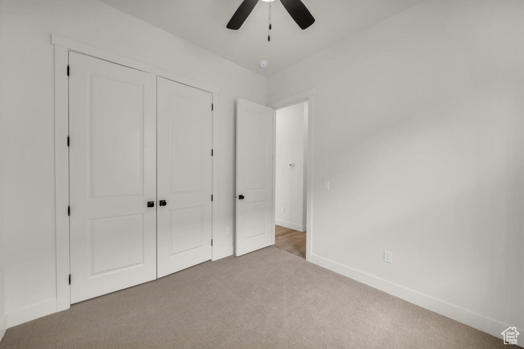 Unfurnished bedroom with a closet, ceiling fan, and dark carpet