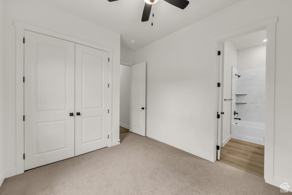 Unfurnished bedroom with light carpet, ensuite bath, a closet, and ceiling fan