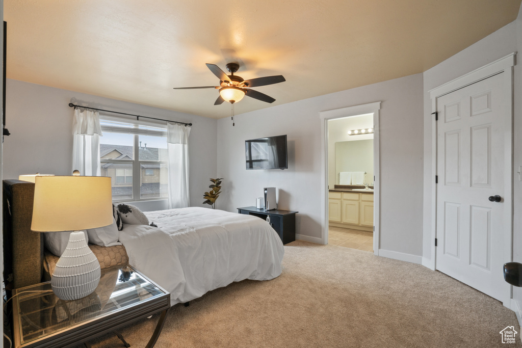 Bedroom with connected bathroom, light colored carpet, and ceiling fan