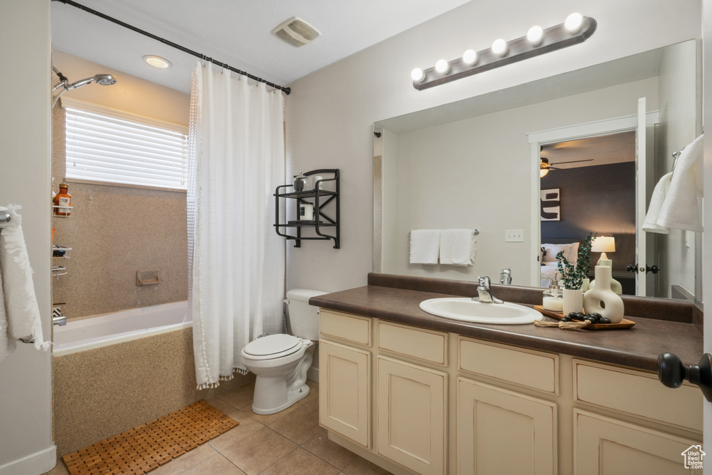 Full bathroom with toilet, ceiling fan, shower / bath combo with shower curtain, tile floors, and vanity