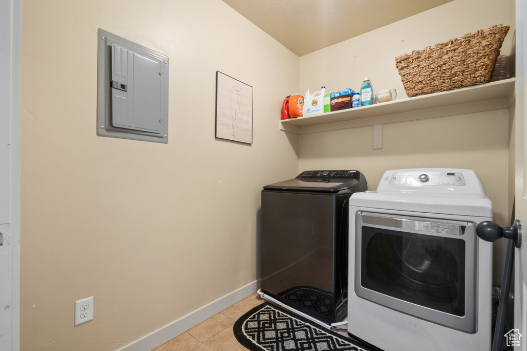 Washroom with washing machine and clothes dryer and light tile flooring