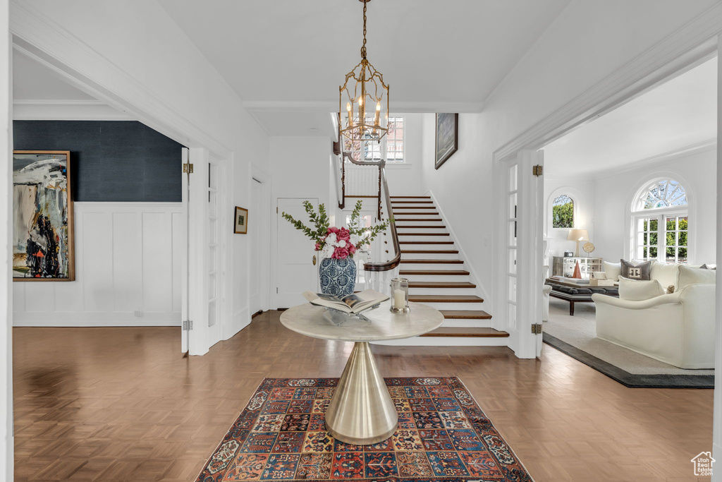 Entrance foyer with dark parquet floors and a notable chandelier