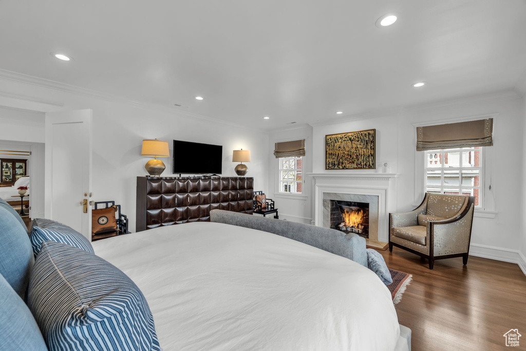 Bedroom featuring a high end fireplace, dark wood-type flooring, and crown molding
