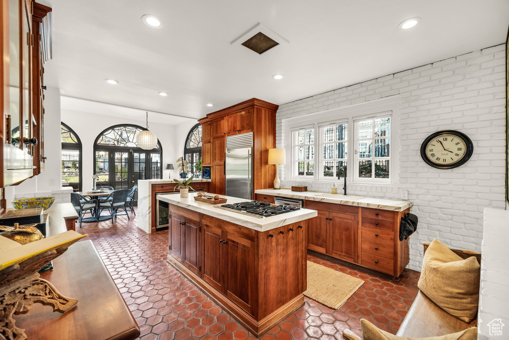 Kitchen featuring dark tile flooring, a kitchen island, stainless steel appliances, and a wealth of natural light