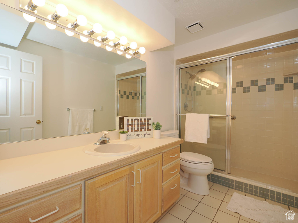 Bathroom featuring walk in shower, toilet, vanity, and tile flooring