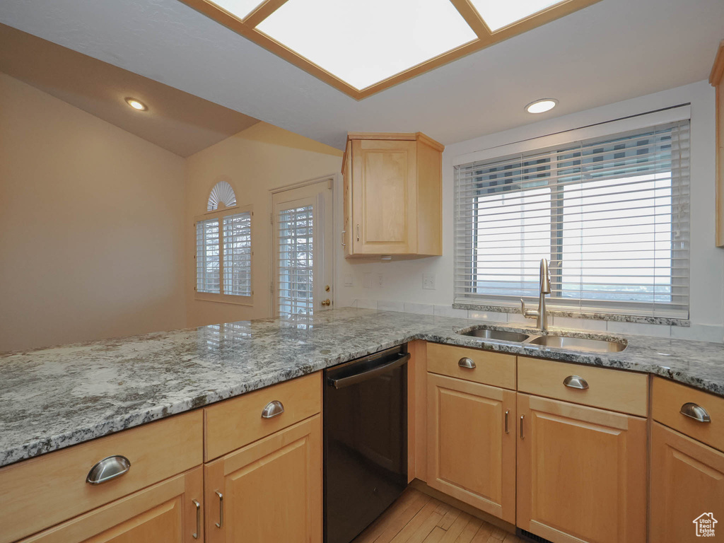 Kitchen with light stone counters, a healthy amount of sunlight, black dishwasher, and sink
