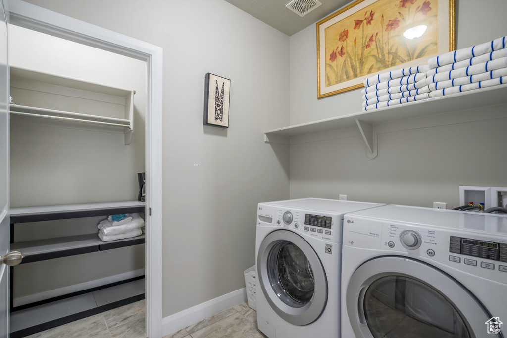 Laundry room featuring hookup for a washing machine, light tile floors, and washing machine and clothes dryer