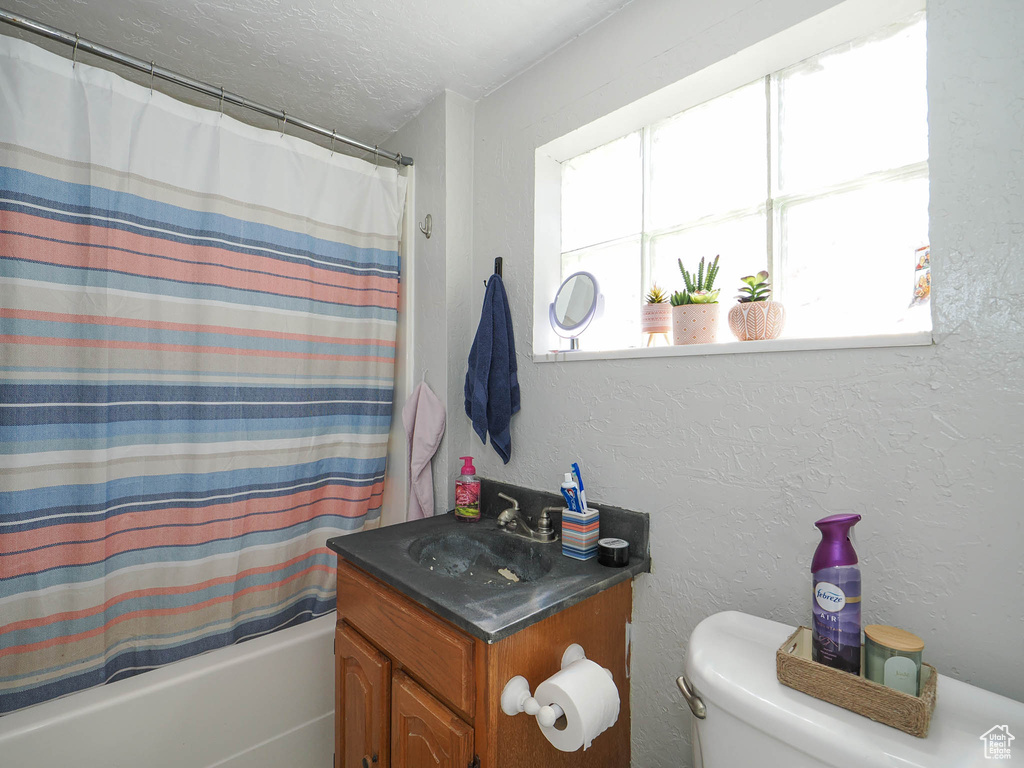 Full bathroom with shower / bathtub combination with curtain, vanity, and toilet