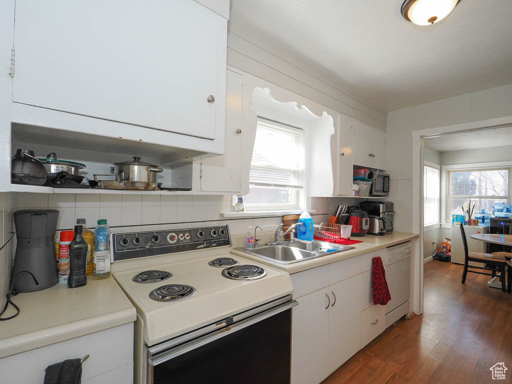 Kitchen featuring backsplash, sink, dark hardwood / wood-style flooring, white appliances, and white cabinetry