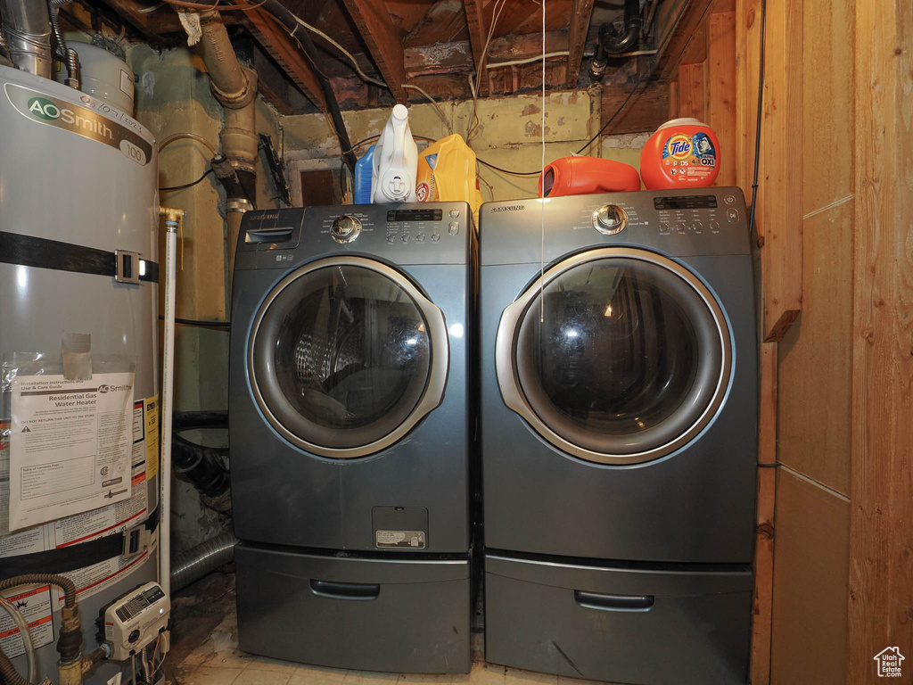 Laundry area featuring wood walls, washer and clothes dryer, and secured water heater