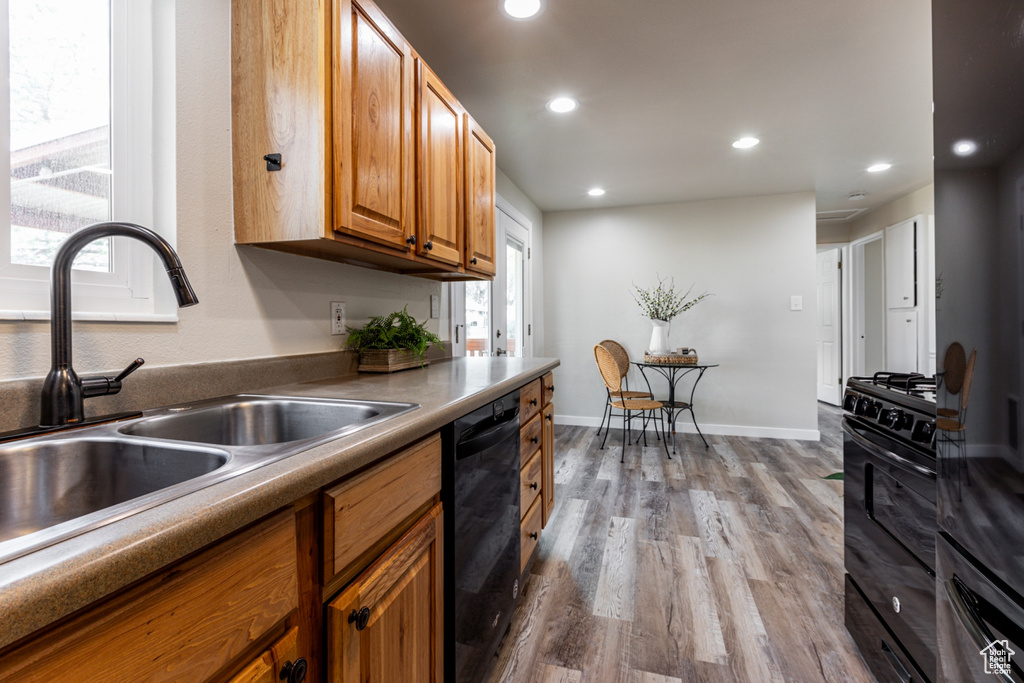 Kitchen featuring black appliances, sink, and light hardwood / wood-style flooring