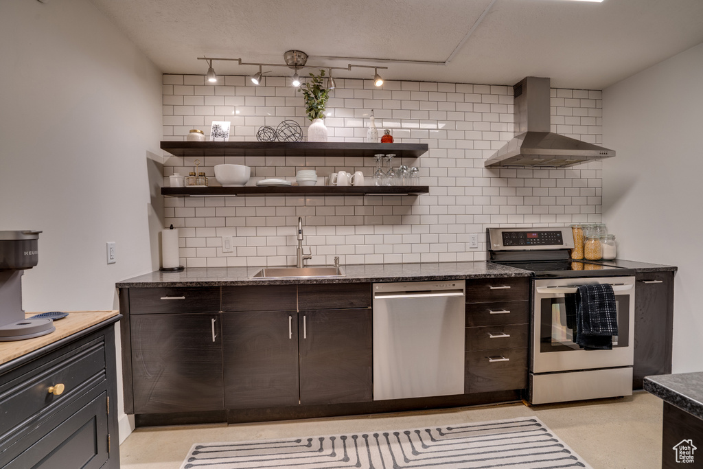 Kitchen featuring backsplash, sink, appliances with stainless steel finishes, and wall chimney range hood