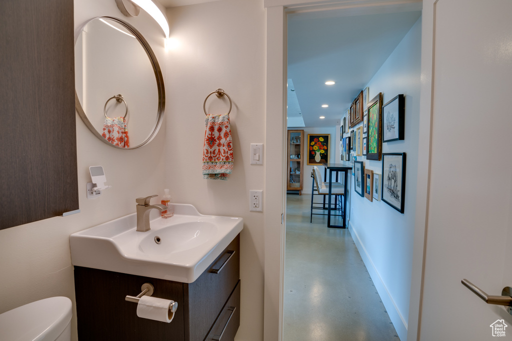Bathroom with toilet, concrete floors, and vanity with extensive cabinet space