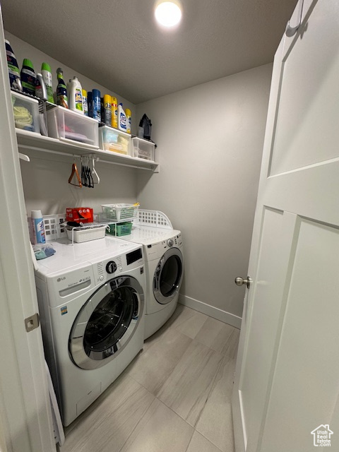 Washroom with light tile floors and washing machine and clothes dryer