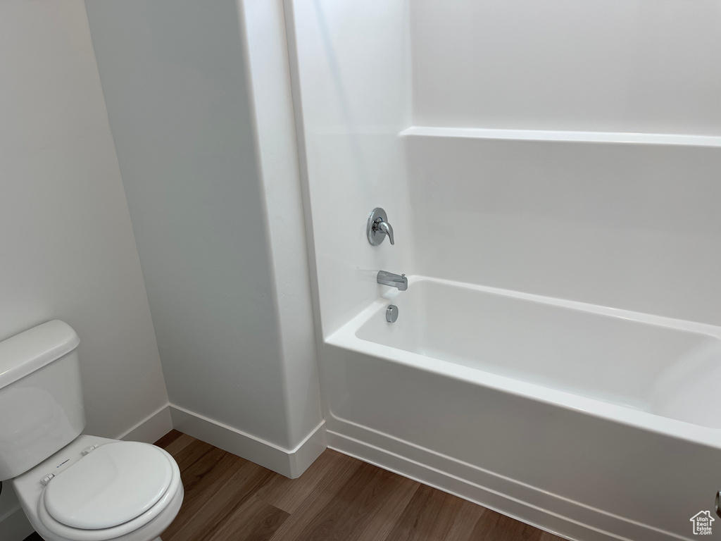 Bathroom with hardwood / wood-style floors, toilet, and tub / shower combination