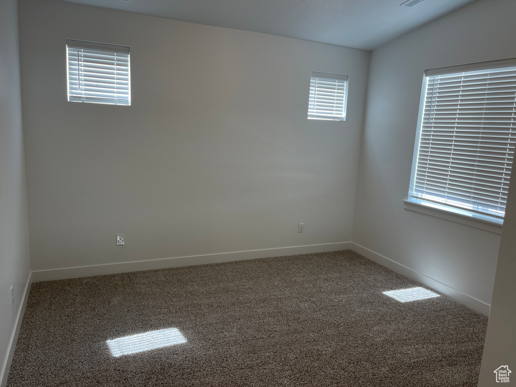 Spare room featuring vaulted ceiling and dark colored carpet