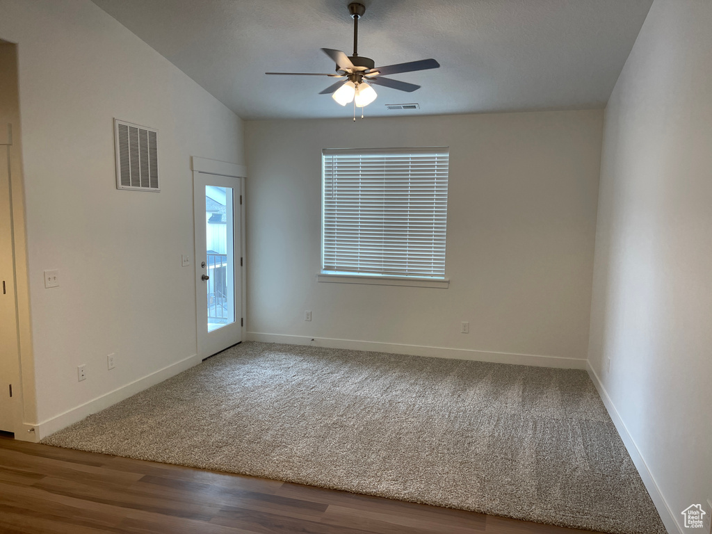 Spare room featuring light carpet, vaulted ceiling, and ceiling fan