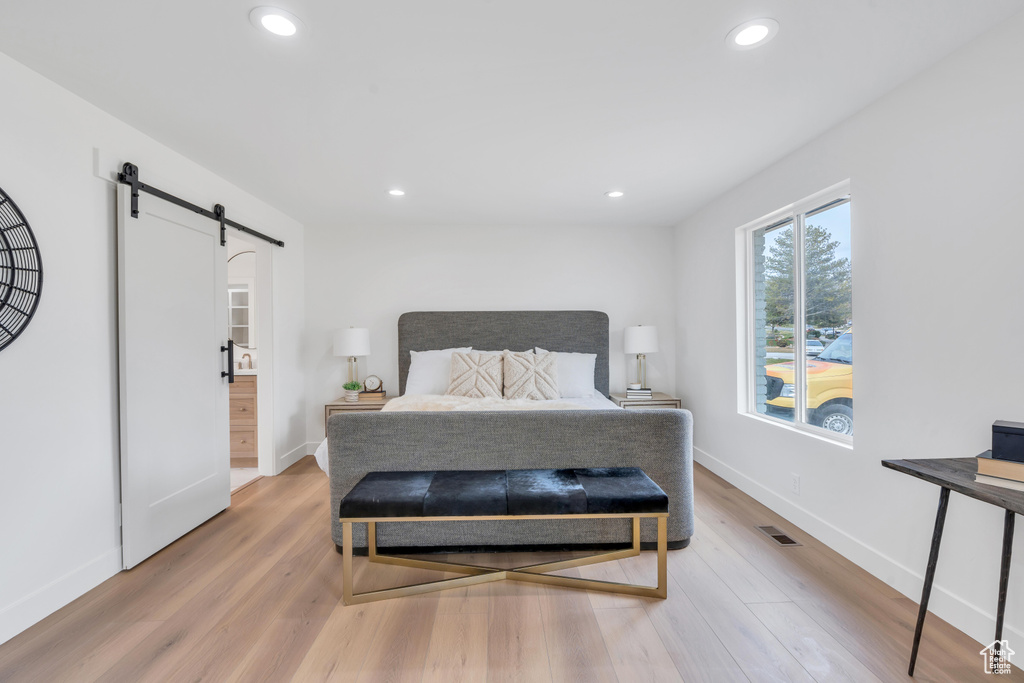 Bedroom featuring a barn door and light hardwood / wood-style flooring