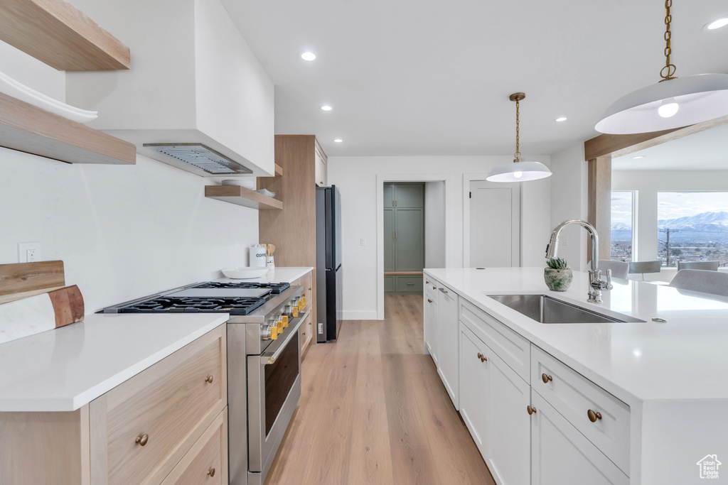 Kitchen featuring a kitchen island with sink, appliances with stainless steel finishes, sink, light hardwood / wood-style flooring, and pendant lighting