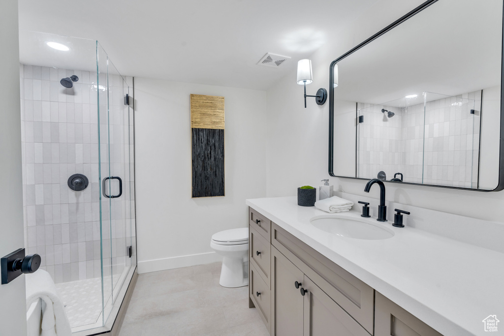 Bathroom featuring oversized vanity, toilet, a shower with shower door, and tile flooring