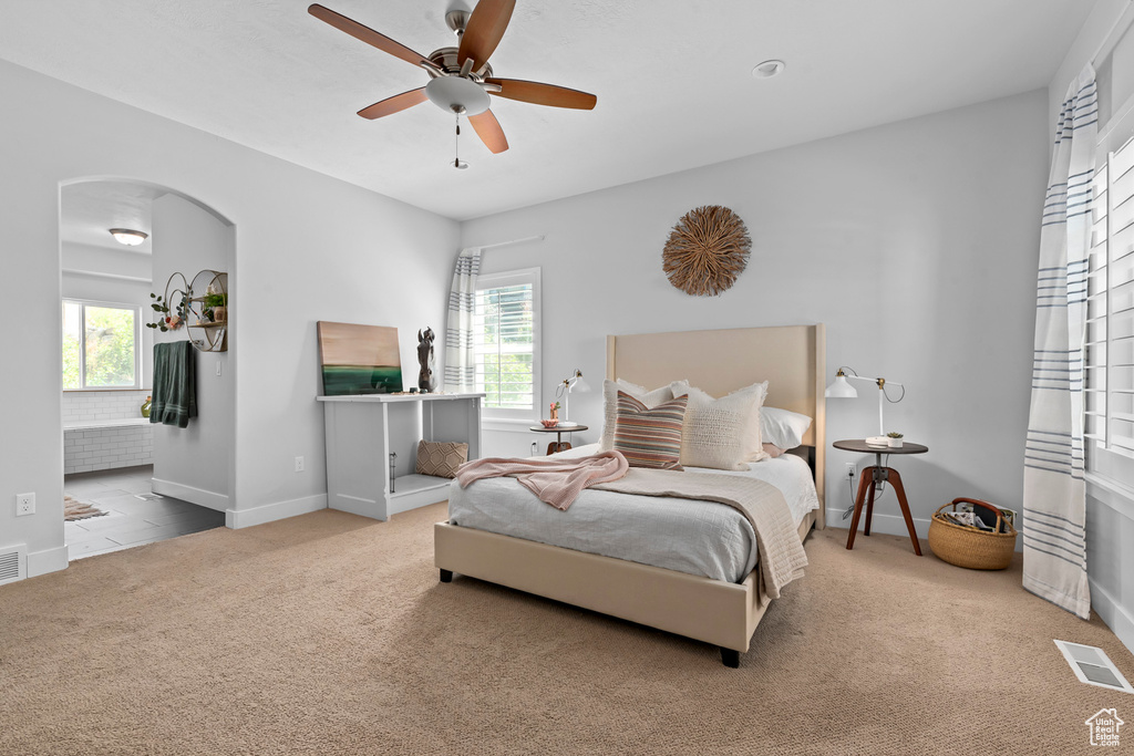 Bedroom with light carpet, ceiling fan, and multiple windows