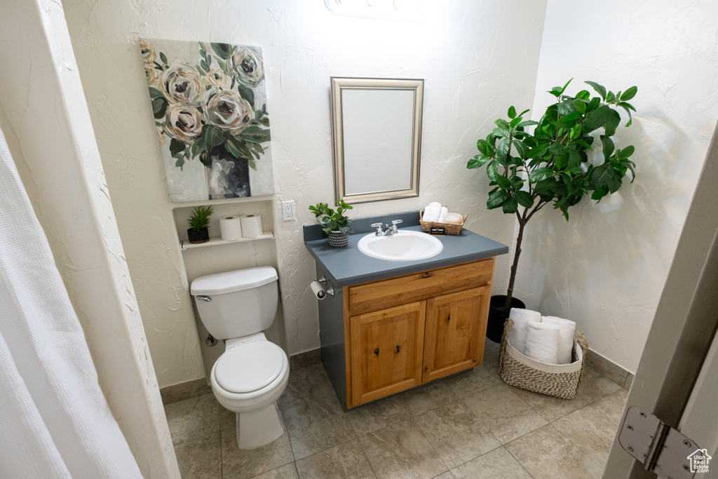 Bathroom with toilet, vanity, and tile flooring