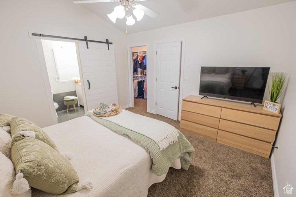 Bedroom featuring ceiling fan, a spacious closet, carpet flooring, a barn door, and lofted ceiling