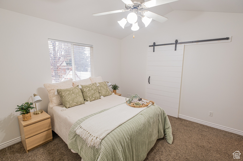 Carpeted bedroom with a barn door, ceiling fan, and lofted ceiling
