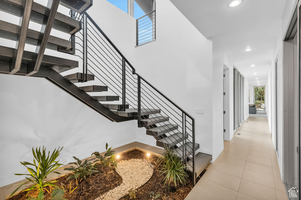 Stairway with a high ceiling, light tile floors, and a wealth of natural light