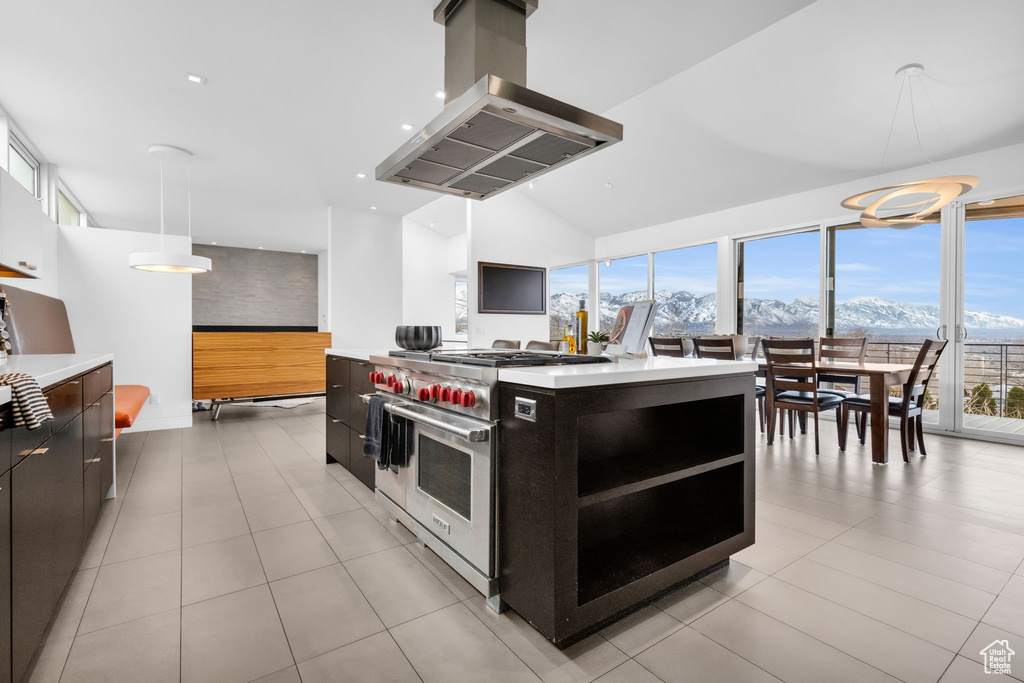 Kitchen featuring a healthy amount of sunlight, light tile floors, island range hood, range with two ovens, and pendant lighting