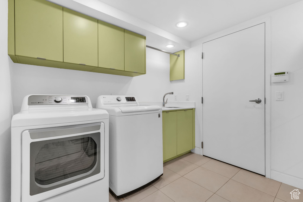 Laundry room featuring cabinets, light tile flooring, sink, and washer and clothes dryer