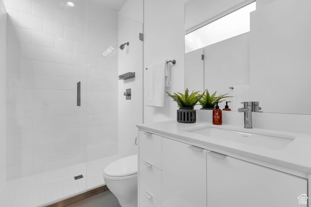 Bathroom with toilet, a shower with shower door, and large vanity