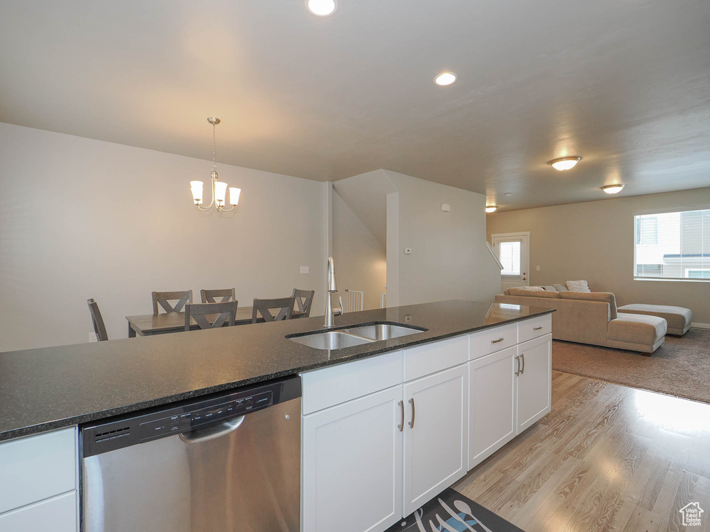 Kitchen with sink, a chandelier, stainless steel dishwasher, decorative light fixtures, and white cabinetry