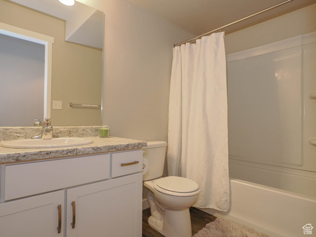 Full bathroom featuring shower / tub combo, toilet, vanity, and wood-type flooring