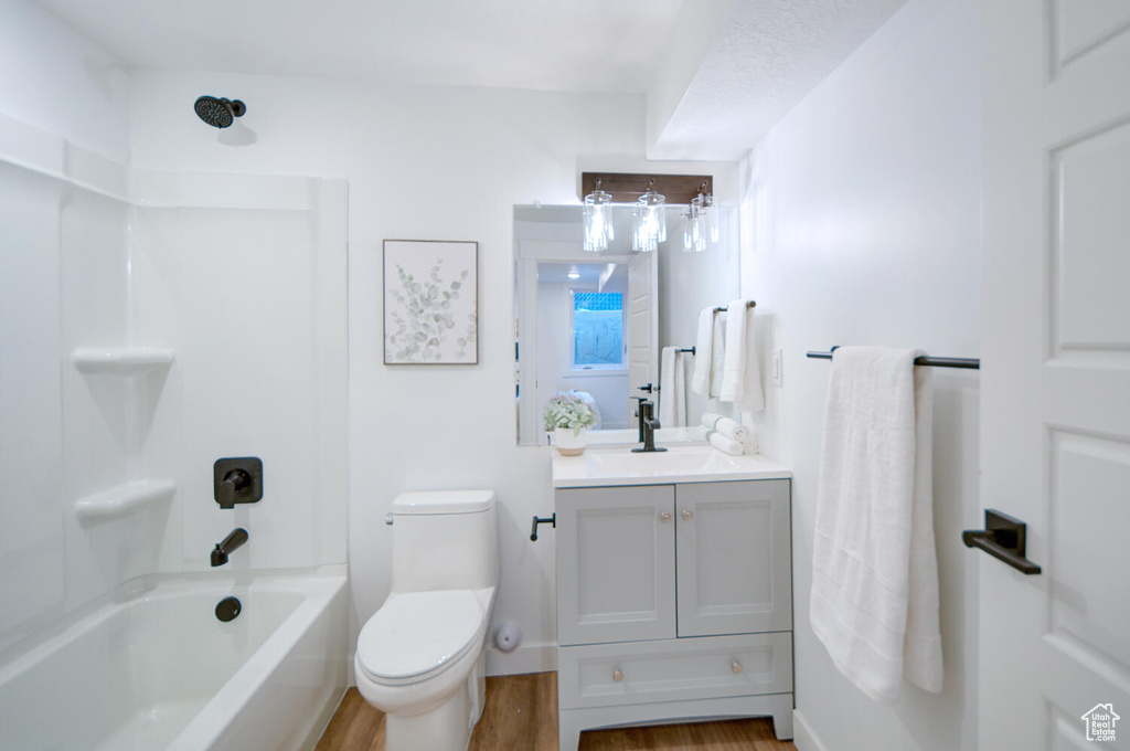 Full bathroom featuring hardwood / wood-style flooring,  shower combination, large vanity, and toilet