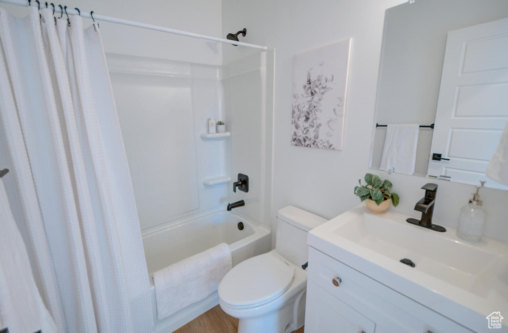 Full bathroom featuring toilet, vanity, shower / bathtub combination with curtain, and wood-type flooring