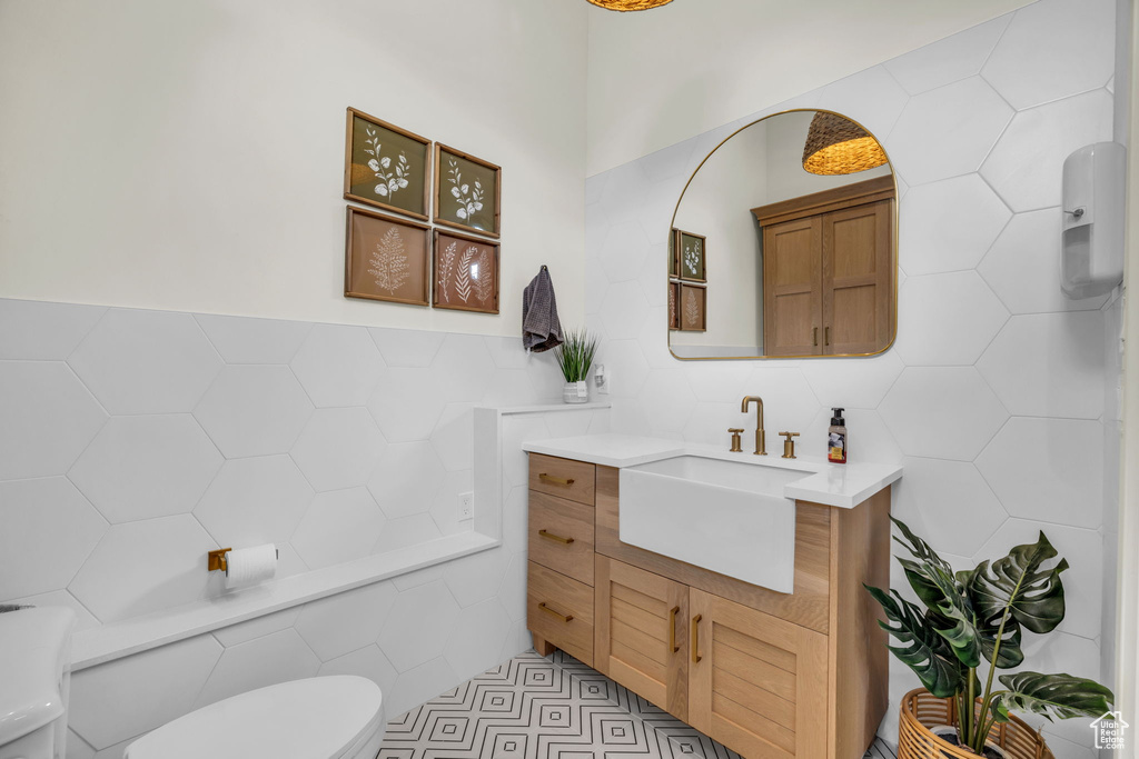 Bathroom with tile walls, toilet, vanity, and tile floors