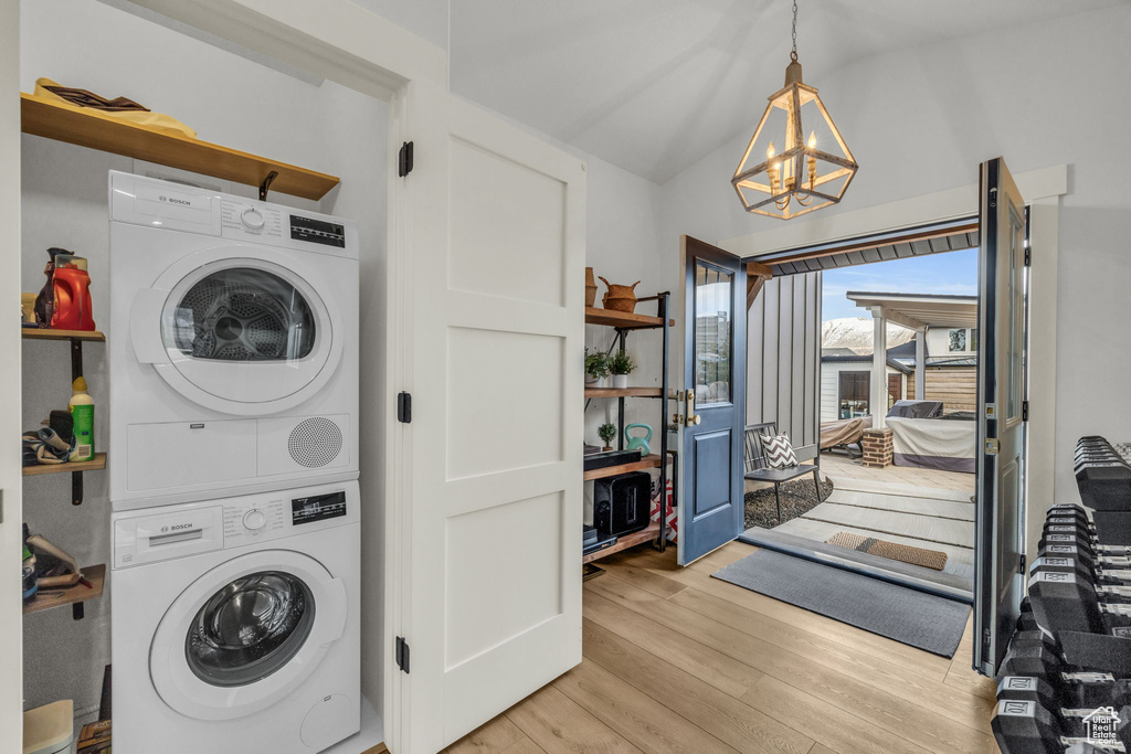 Laundry area featuring stacked washer / dryer, a notable chandelier, and light hardwood / wood-style flooring