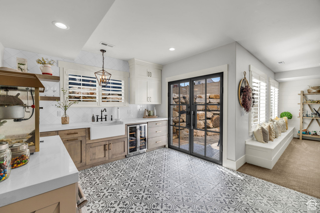 Kitchen featuring pendant lighting, light tile floors, sink, an inviting chandelier, and tasteful backsplash
